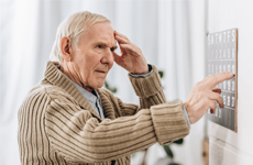 [Translate to Italian:] Old man touching his forehead standing infront of an button panel