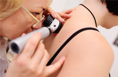 [Translate to Italian:] Physician looking on skin of patient with an miscroscope instrument