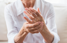 [Translate to Italian:] Person in white blouse holding left hand with right hand